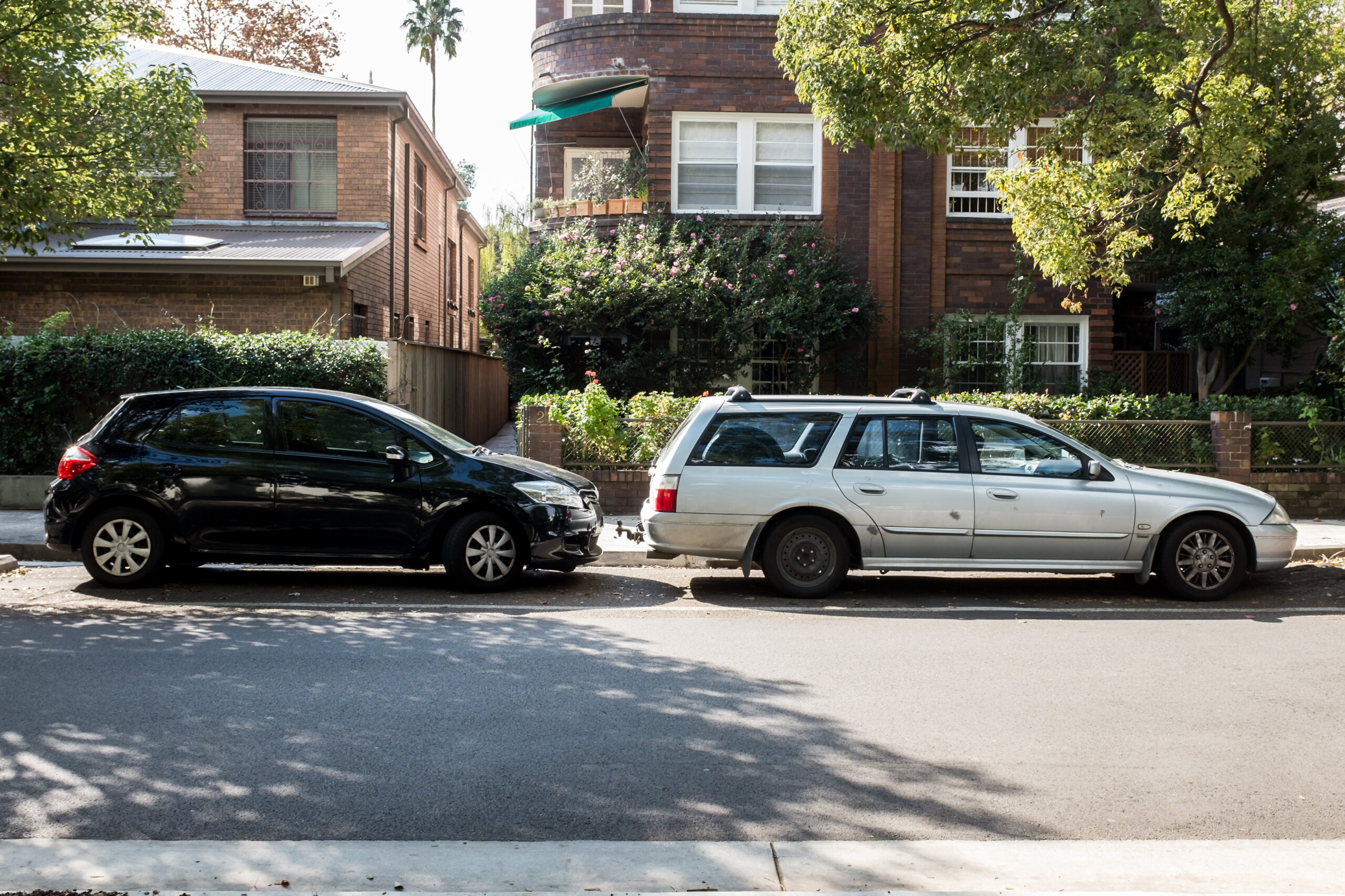 old and new car parked in a suburban street